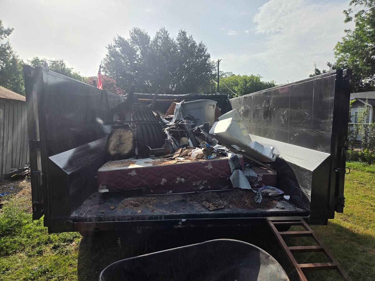 Dump trailer loaded with a mattress, furniture, and other household items