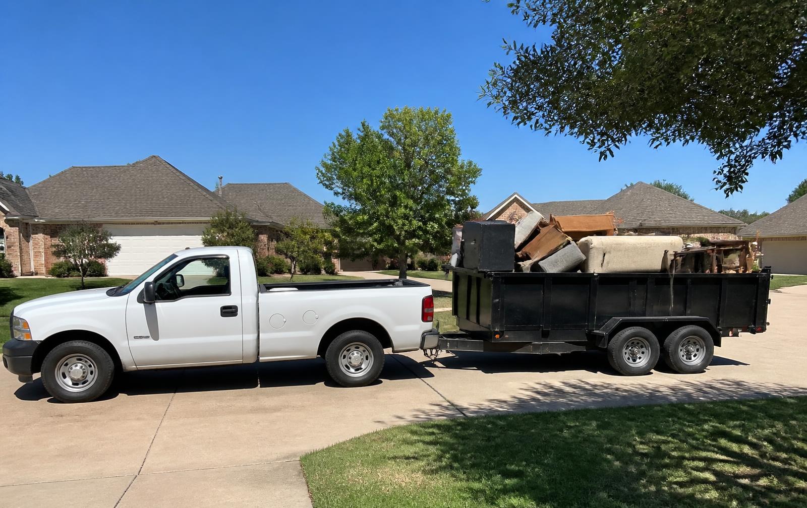 Truck and dump trailer loaded with hauled-away household junk in a Gainesville driveway